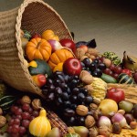 Overturned basket of fall vegetables and fruits: pumpkin, apple, gourd, and grapes